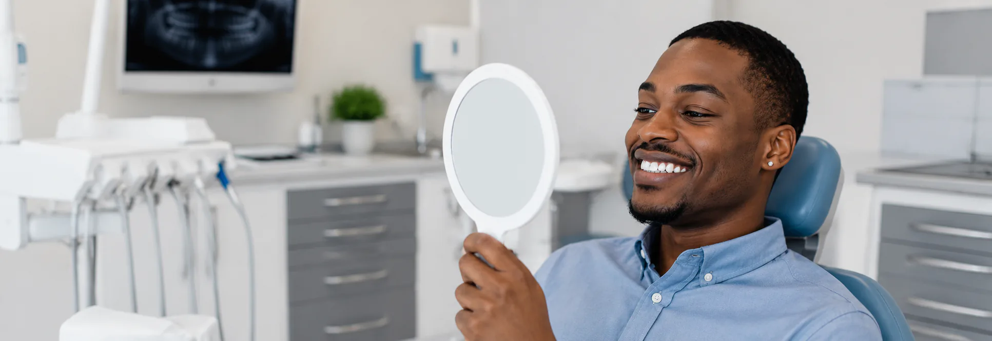 Man in dental chair holding mirror smiling — General Dentistry at PermaSmile! in Ottawa
