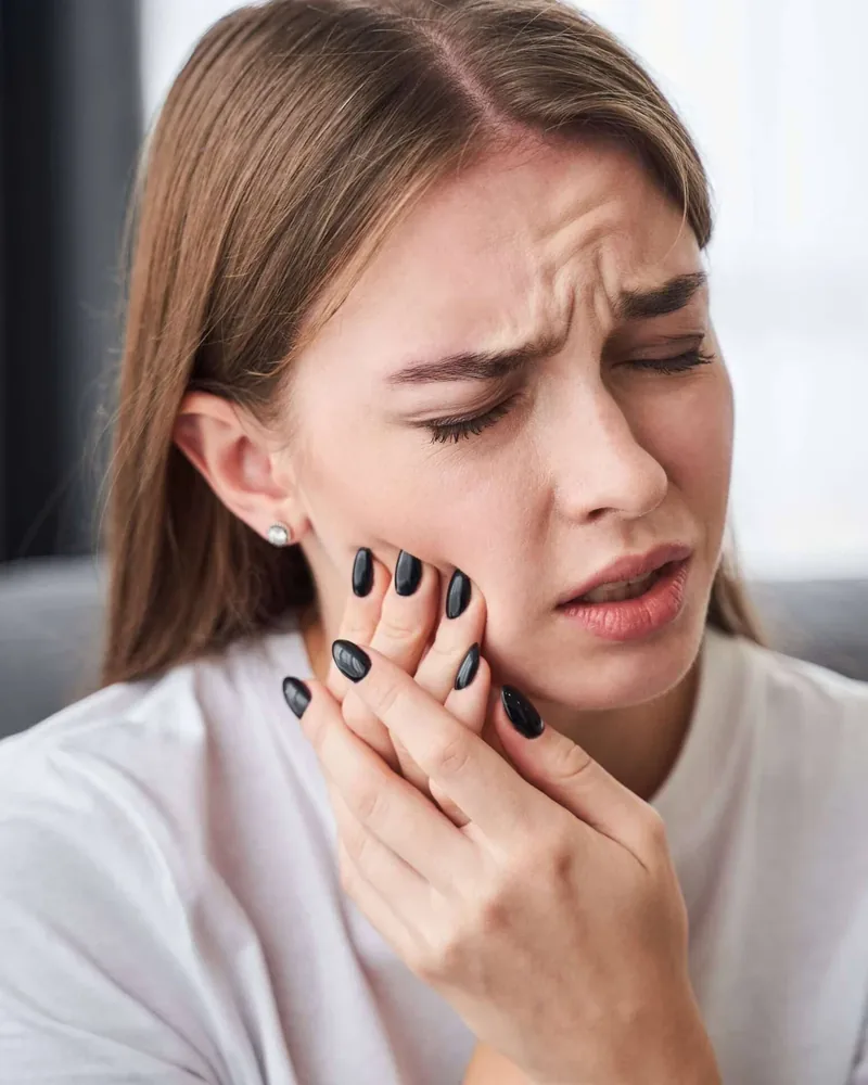 A woman holding her jaw, waiting to be seen for a dental emergency